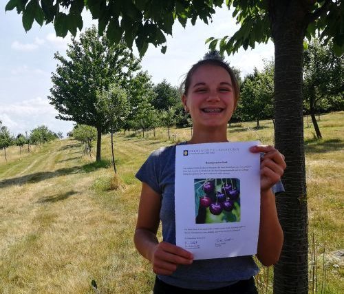 Foto einer Baumpatin mit Urkunde im Obstsortengarten der Oberlausitz